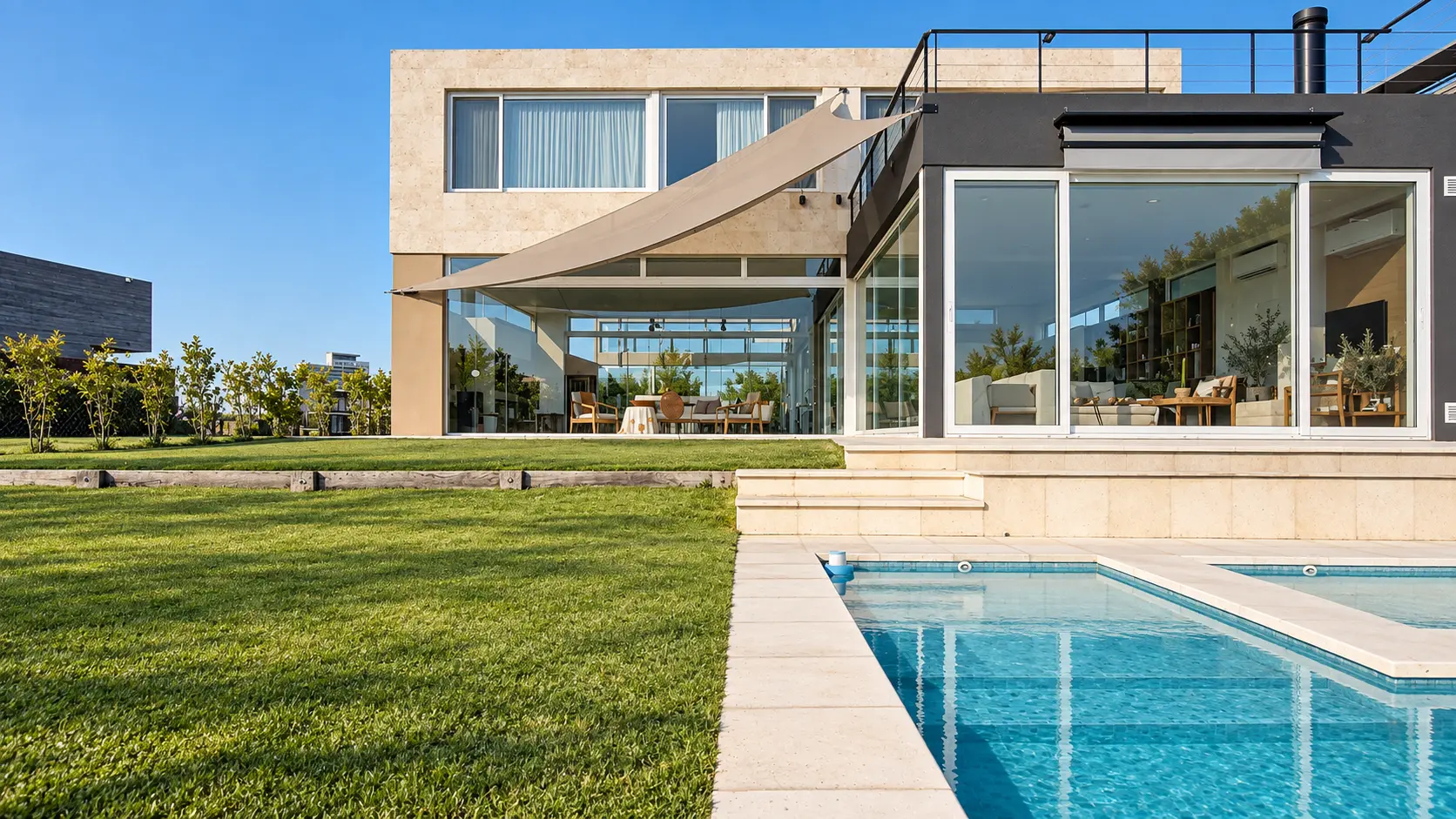 Galería de una casa cerrada con paños de vidrio, frente a la piscina
